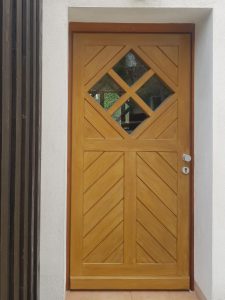 eine Eingangstüre aus Holz mit rautenförmigem Fensterausschnitten
