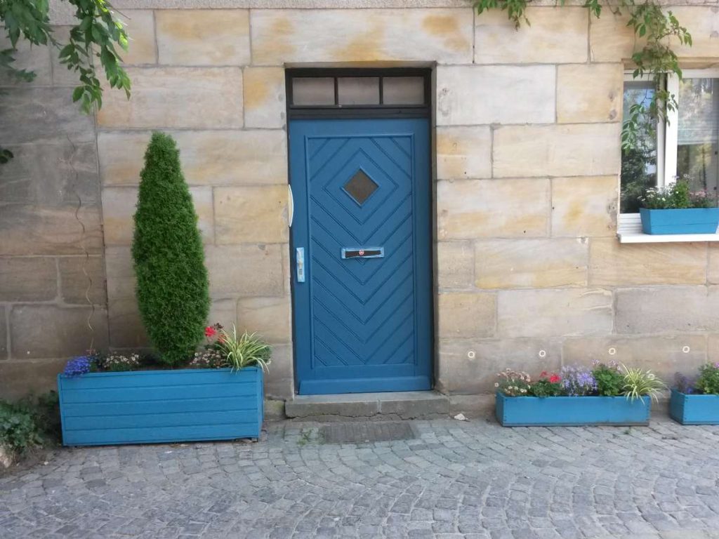 eine blaue Haustür in einem Sandsteingebäude auf dem Land